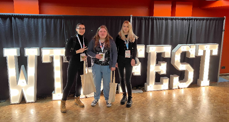 Bethany and two colleagues in front of the ‘WTSFEST’ sign